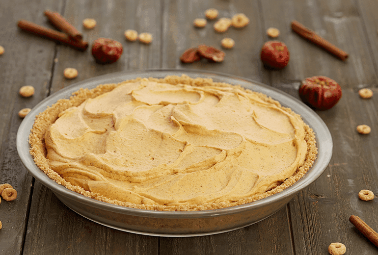 Gluten Free Pumpkin Cream Pie with a Honey Nut Cheerios crust in a shallow metal bowl with ingredients scattered round it.